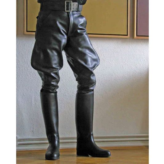 Black leather riding breeches with a black belt, worn with matching tall black leather riding boots, shown on a model standing on a metal stool in an indoor setting.