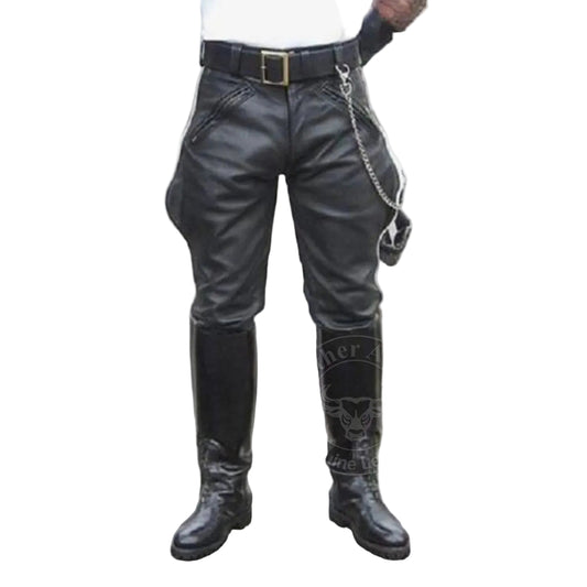 A person wearing black leather pants with a logo on the side, standing on a street with a backdrop of a leather store.