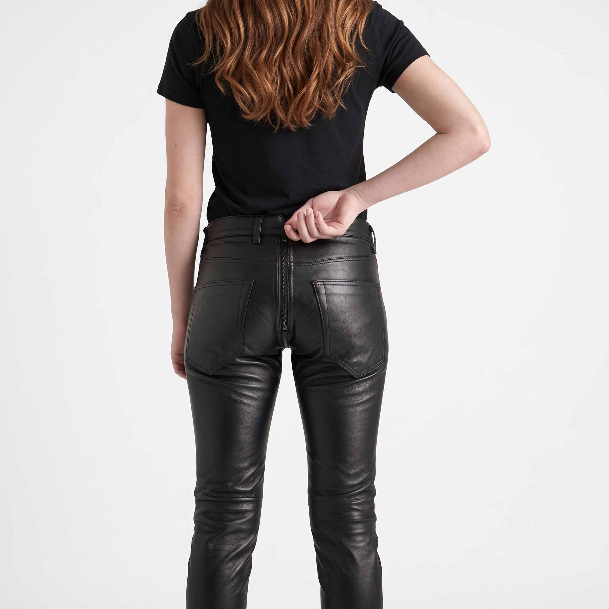 Close up view of hands unzipping the two way rear zipper on mens black cowhide leather trousers