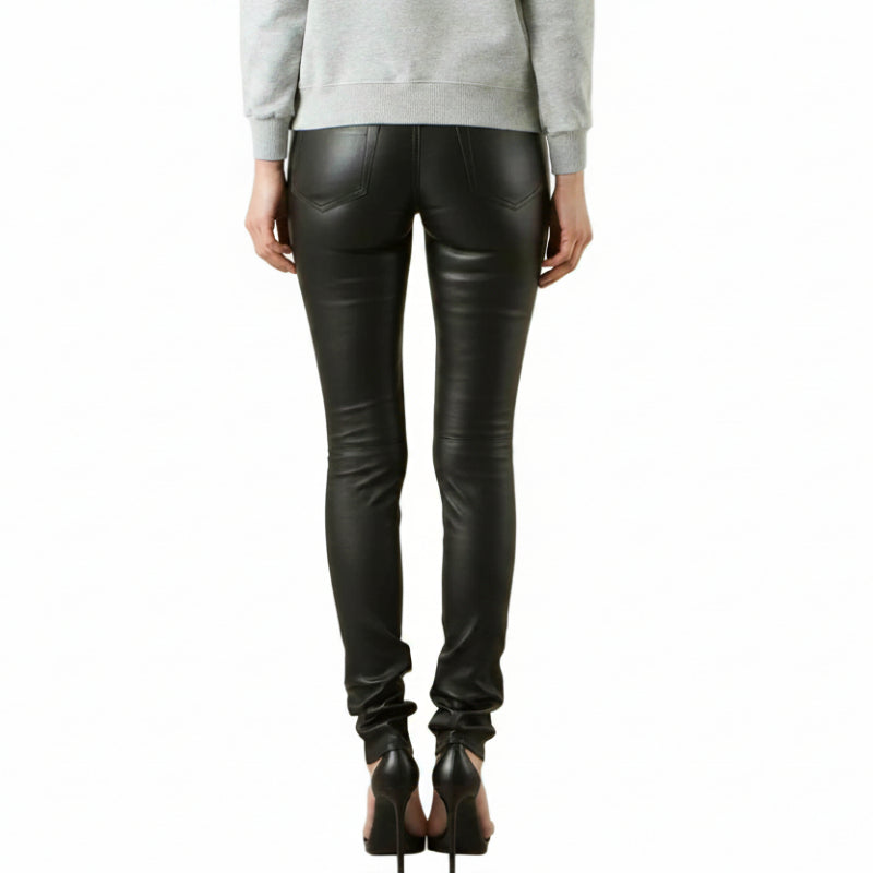 Rear view of a model wearing black lambs leather skinny jeans with a gray graphic print on the left leg, paired with a light gray sweatshirt and black high heels, against a white background.