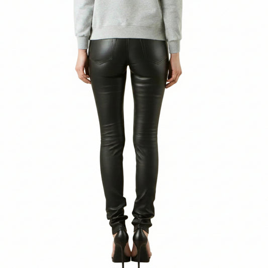 Rear view of a model wearing black lambs leather skinny jeans with a gray graphic print on the left leg, paired with a light gray sweatshirt and black high heels, against a white background.
