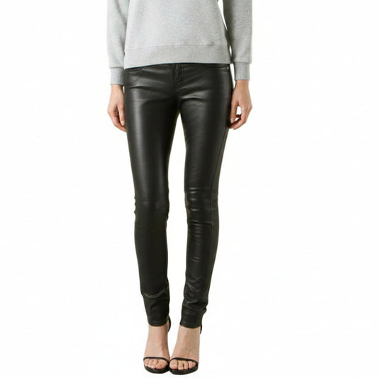 A model from the waist down wearing black lsmbs leather skinny pants with a tonal graphic print on the lower left leg, paired with a light gray sweatshirt and black high-heeled sandals, against a plain white background.