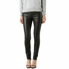 A model from the waist down wearing black lsmbs leather skinny pants with a tonal graphic print on the lower left leg, paired with a light gray sweatshirt and black high-heeled sandals, against a plain white background.