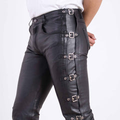 Close up side view of high waisted black leather pants showing silver roller buckle straps along the hip and thigh