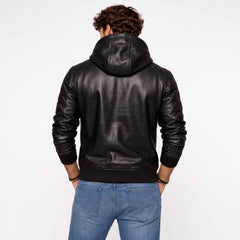 Back view of man wearing tailored black leather hoodie showing clean back yoke, hood drape, and ribbed waistband over blue jeans