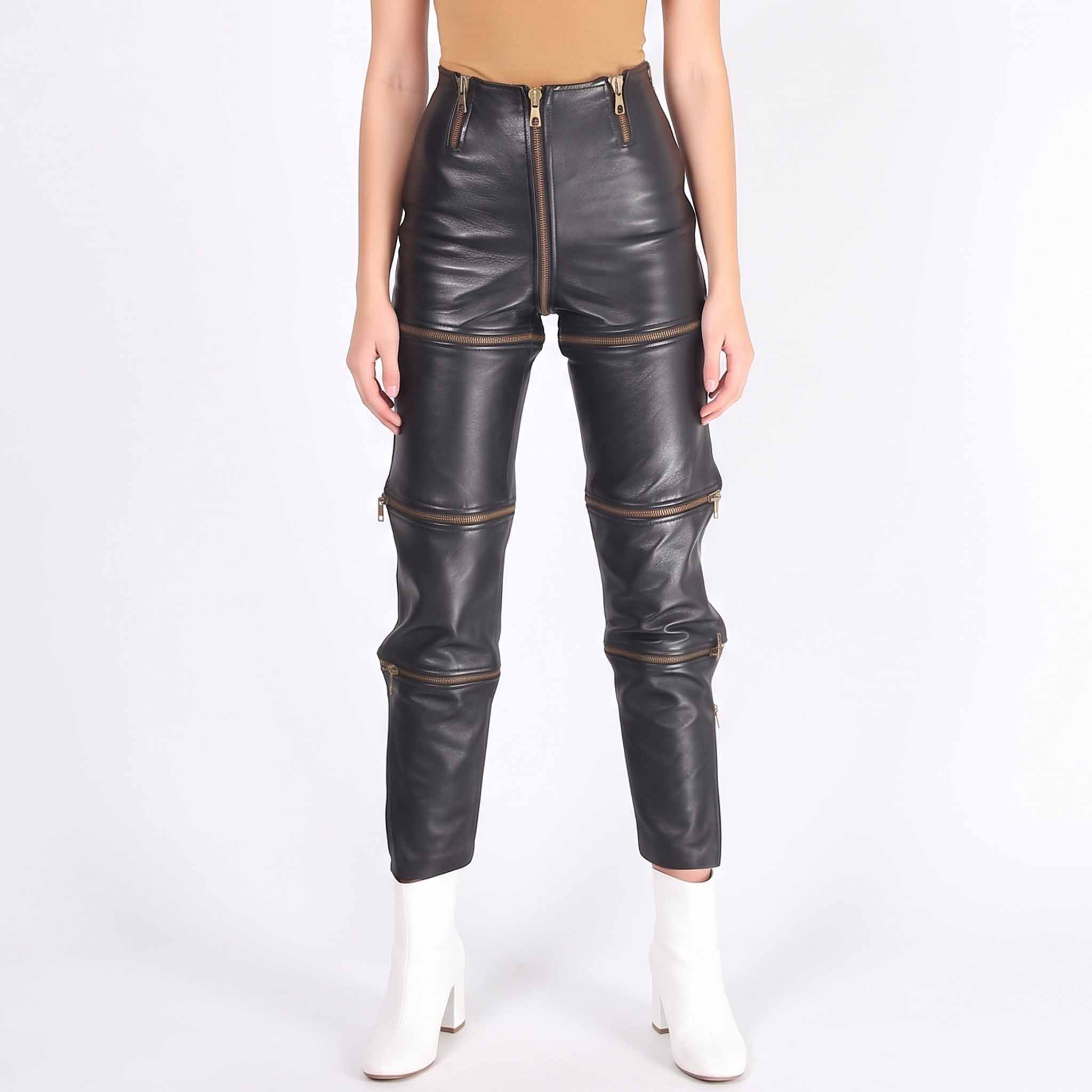 Direct front view of female model in black leather zip off trousers showing center zipper and gold horizontal leg zippers