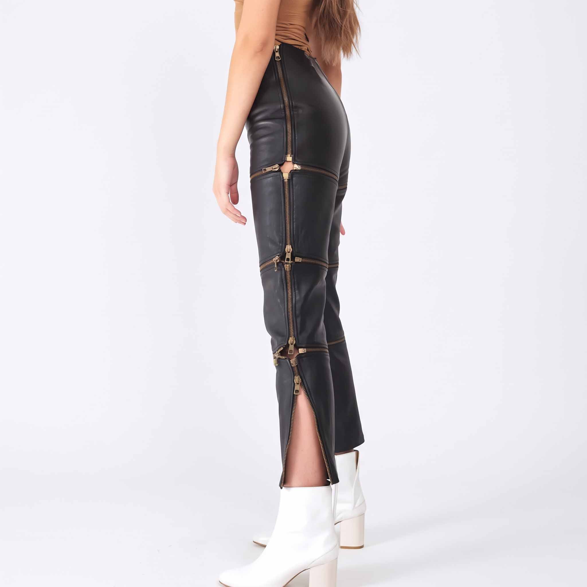 Side profile shot of woman wearing black leather zip off pants showing open side zipper slits and gold zipper pull details