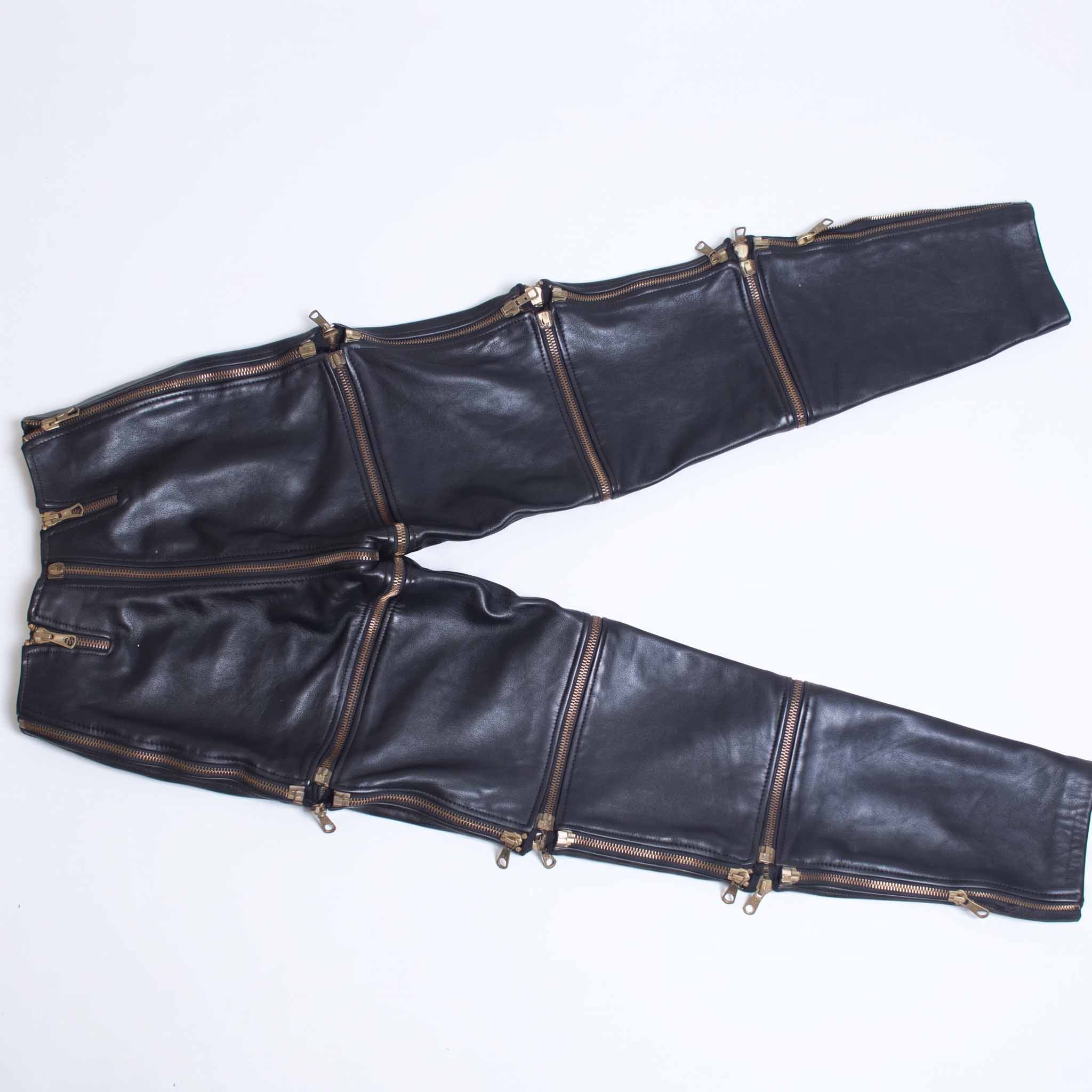 Flat lay view of handmade black leather convertible pants showing all horizontal and vertical zip off sections fully spread