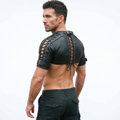 Rear three-quarter studio shot of man in black leather bolero harness detailing rear neck buckle closure and adjustable arm cuffs