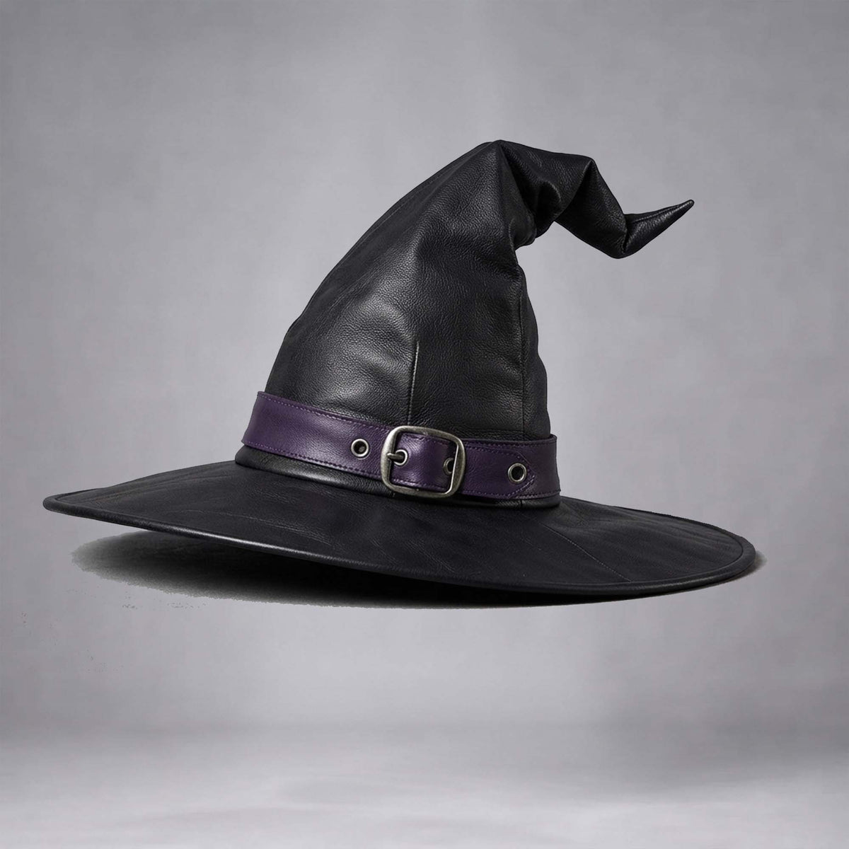 Studio shot of the handmade black leather witch hat accented with a purple band and metal buckle.