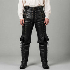 Front studio view of a man wearing black real leather Renaissance pants with side lacing, waist buckles, and attached boot covers against a neutral grey backdrop.
