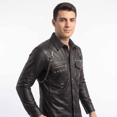 Side angled portrait of smiling man wearing tailored black leather alternative shirt showing snap cuffs and silver tone hardware