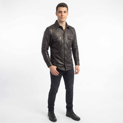 Full body perspective of model in black leather punk rock overshirt and denim jeans posing against seamless white background