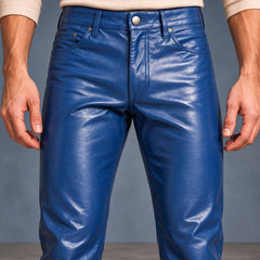 Close-up shot of men's blue cowhide leather jeans displaying front zip fly, silver shank button, coin pocket, and rivet details