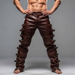 Full front view of muscular man wearing handmade brown cowhide leather pants with multiple side roller buckle straps on grey background