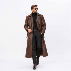 Full length front view of handsome man walking in handmade brown genuine leather long trench coat open over dark turtleneck and trousers