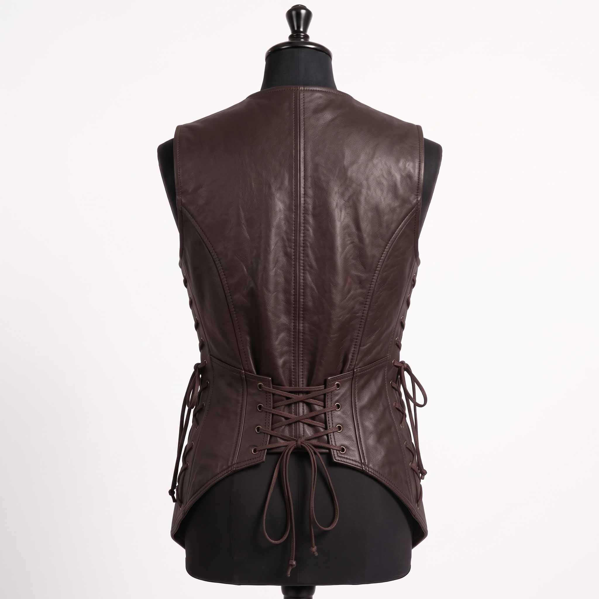 Close up side view of dark brown leather vest detailing brass side lacing grommets, leather ties, roller buckle belt, and cargo hip pocket