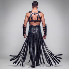 Back full body view of black leather warrior harness costume showing rear corset lacing on waist belt, back strap harness, and flowing fringe