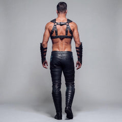 Rear view of man walking away in black genuine leather chest harness and tailored leather pants showing back buckle straps and clean rear pockets