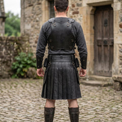 Back view of man wearing black cowhide pleated leather kilt and back plate armor with leather vambraces outside castle door