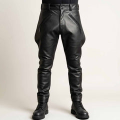 Front view of a man wearing black cowhide leather breeches featuring a flared thigh design, zippered front pockets, and structured waistband paired with boots.