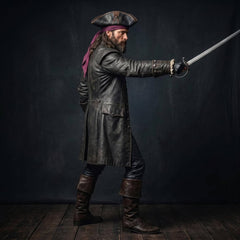 Side profile view of pirate captain pointing rapier sword showing wide folded cuffs and long leather coat tails