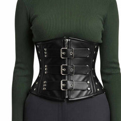 Front view of a model wearing a black genuine leather underbust corset with silver zipper and three front buckles over a dark green sweater.
