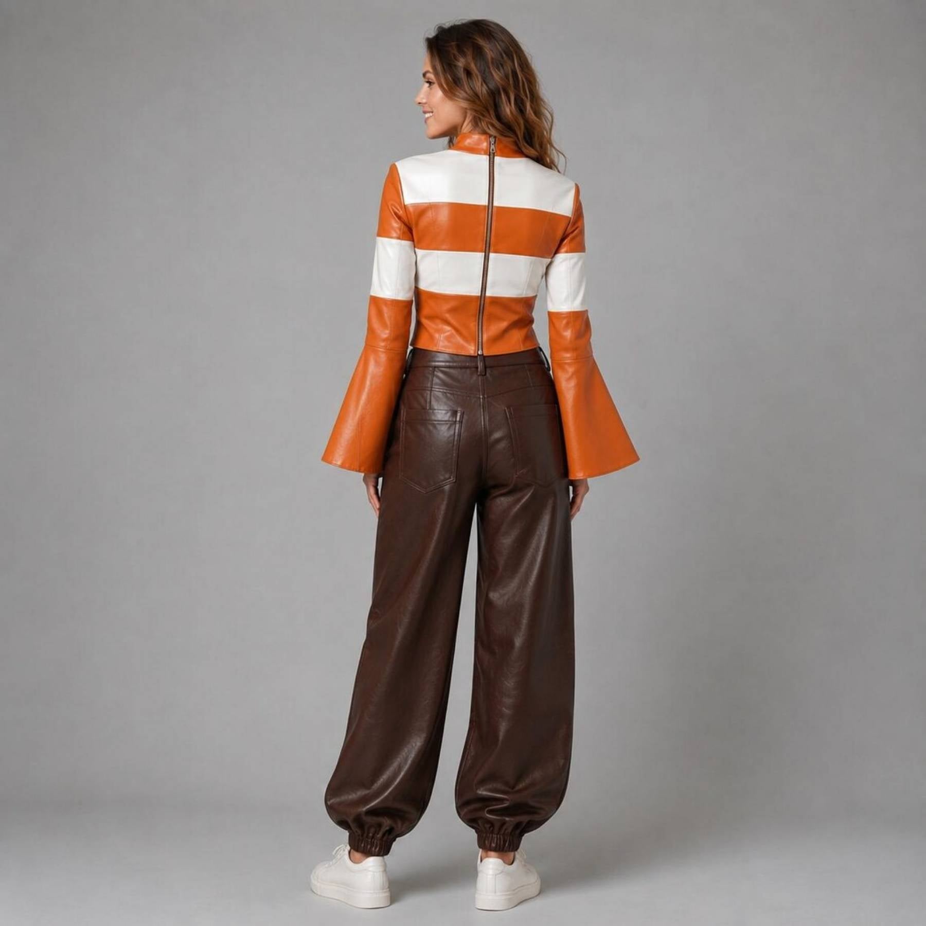 Rear view of the women's genuine leather outfit displaying the back zipper closure on the orange striped top and tailored patch pockets on the brown leather pants