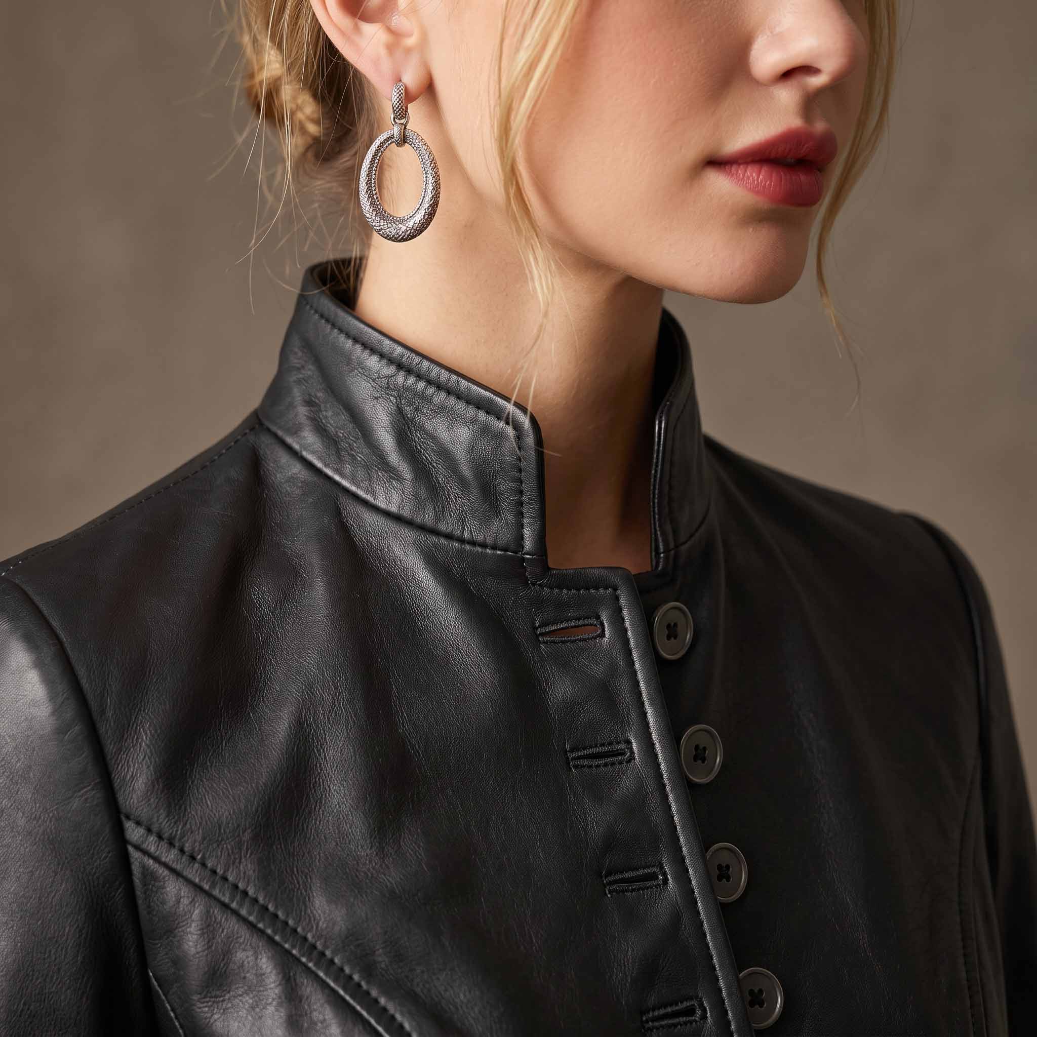 Detailed macro close up of black lambskin leather jacket showing standing mandarin collar, fine stitching, and smoke grey buttons