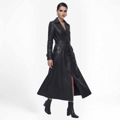 Full length front view of a woman posing in a black leather trench coat with a slight leg slit open.
