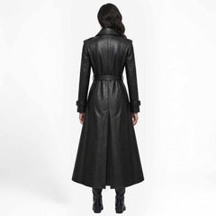 Back view of a woman in a longline black leather duster jacket showcasing the structured paneled seams and rear hem split.