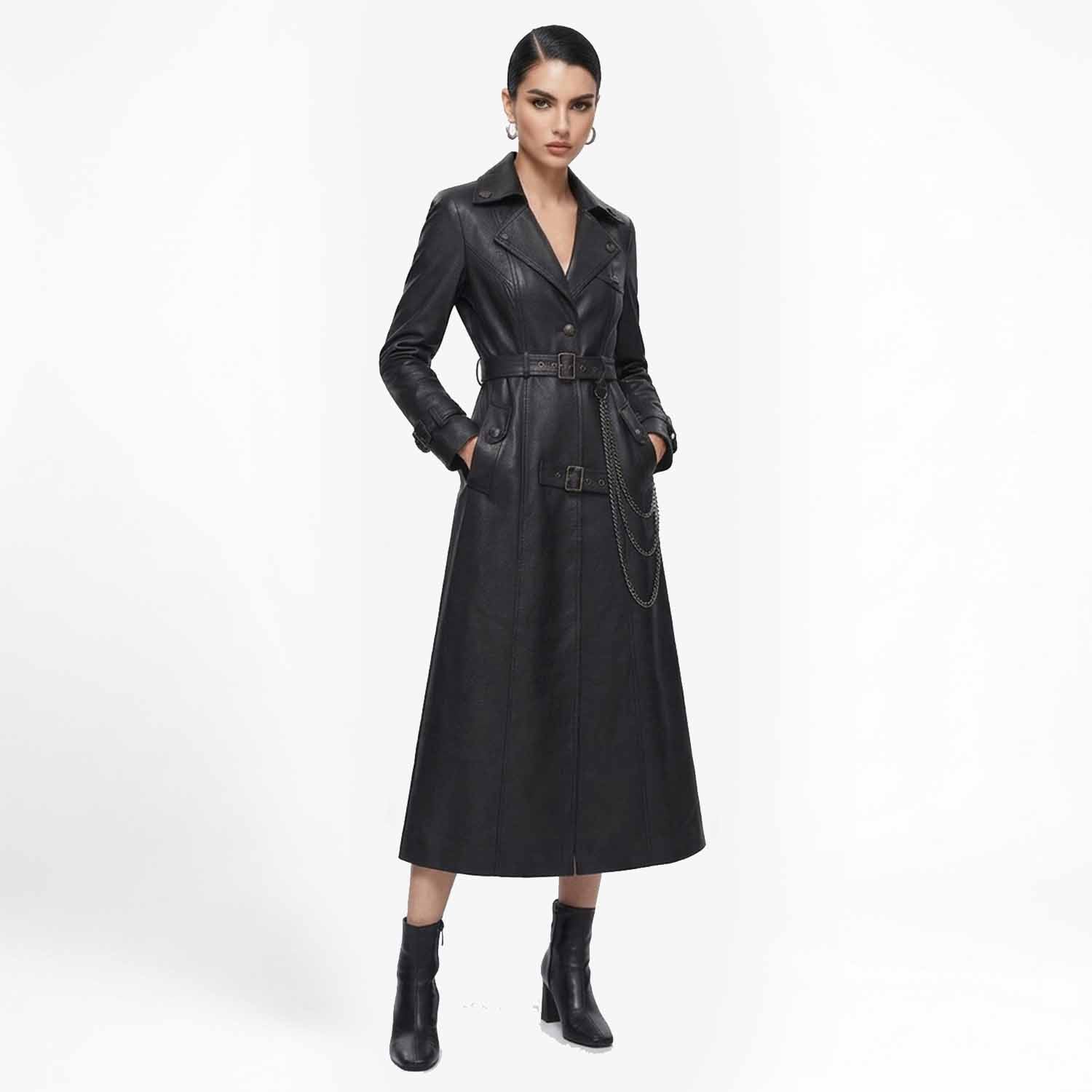 Front view of a woman wearing a long black leather trench coat with a belted waist and hanging chain detail, paired with heeled boots.