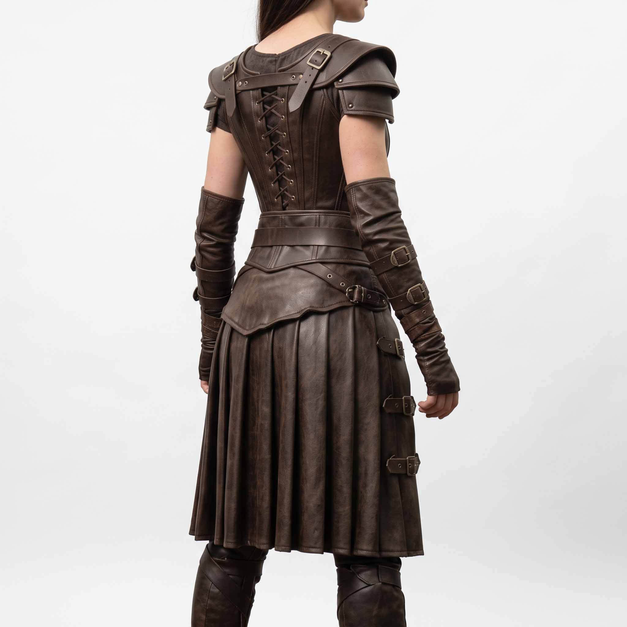 Rear three-quarter studio angle showing back bodice lacing, buckled vambrace arm guards, and pleated leather skirt on white background