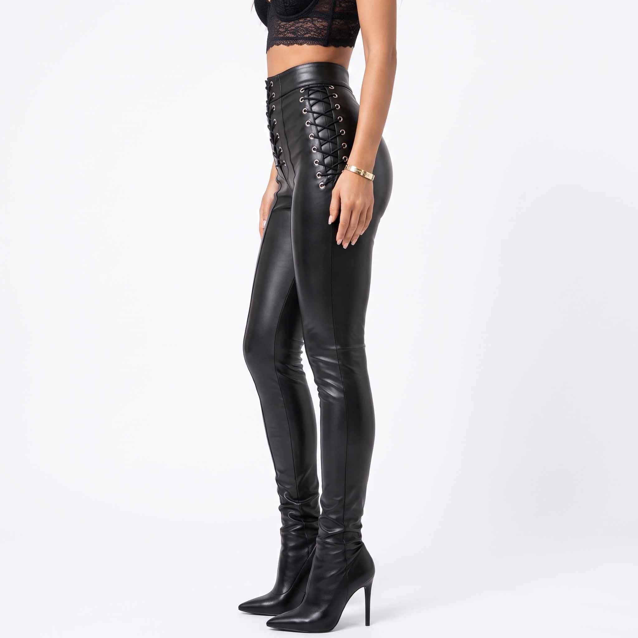 Side profile 90 degree view of female model wearing fitted black leather trousers detailing continuous hip speed lacing and vertical leg seams
