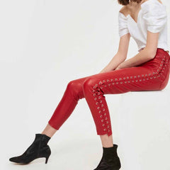 Seated side profile displaying full-length lace-up detail on women's red leather capri pants