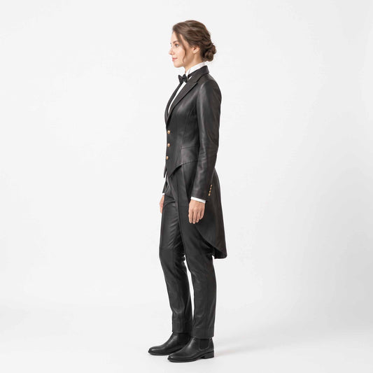 Side profile full length view of woman modeling black genuine sheepskin tuxedo tailcoat suit with peaked lapels and black leather dress boots