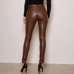 Back view of a woman wearing brown high waisted skinny leather pants showing functional back pockets and ankle zippers.