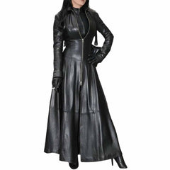 Front view of a woman wearing a long black Nappa leather trench coat featuring a full zipper, high collar, flared skirt, and black leather gloves.